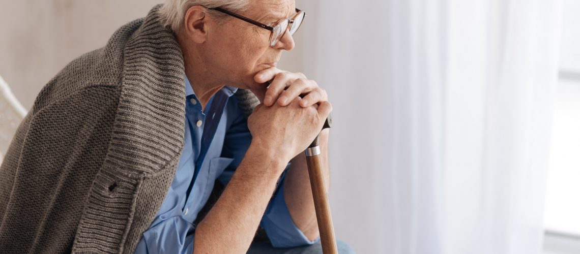 What is life. Gloomy unhappy elderly wan leaning on the walking stick and thinking about life while being depressed